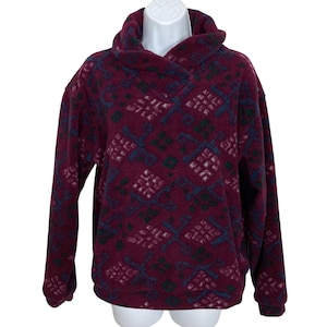 May include: Burgundy fleece pullover with a geometric pattern in shades of blue, green, and white. The pullover has a mock neck and a long sleeve.