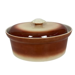 May include: A brown and beige ceramic casserole dish with a lid. The dish has a rounded shape with a lid that features a decorative knob. The colours transition from a dark brown at the base to a lighter beige at the top.