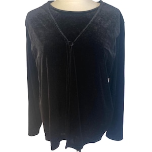 May include: A dark gray velvet long-sleeve top with a V-neckline and a single button closure. The top has a soft, flowing drape and is displayed on a mannequin. The fabric appears to have a subtle sheen.