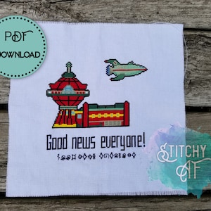 May include: Cross stitch pattern featuring a red and yellow building with a dome, a green spaceship, and the text "Good news everyone!"