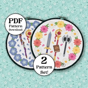 Puede incluir: Dos patrones de punto de cruz en aros de bordado. Uno presenta flores azules, un báculo y el texto "PDF Pattern Download". El otro tiene una espada, un báculo y un hacha rodeados de flores rosas y amarillas. También está presente el texto "2 Pattern Set!"