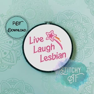 Puede incluir: Un aro de bordado blanco con un diseño de estrella fugaz rosa y arcoíris y el texto "Live Laugh Lesbian".