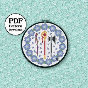 May include: A cross-stitch pattern in a round embroidery hoop. The design features three fantasy weapons surrounded by blue flowers. The text "PDF Pattern Download" is in a circle in the upper left corner. The background is a light blue pattern.
