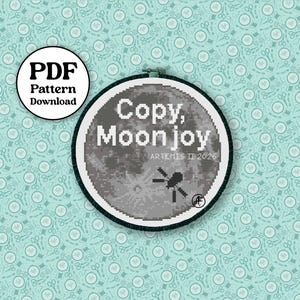 May include: A cross-stitch pattern in a round hoop featuring a grayscale moon with the text "Copy, Moon Joy" and "Artemis II 2026". A PDF pattern download is also included.