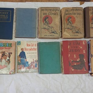 Op de afbeelding: Een verzameling vintage boeken met diverse covers en titels. Titels zijn onder meer "Medical Guide", "Winky Tales & Mystery", "Ruth Fielding", "Lassie" en "Under the North Star". De boeken zijn gerangschikt op een witte ondergrond.