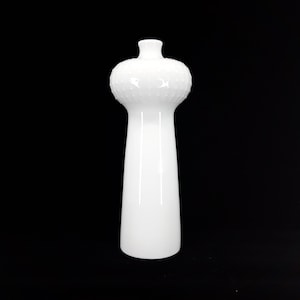 Puede incluir: Un jarrón de cerámica blanco con una parte superior bulbosa texturizada y un cuerpo alto y delgado.