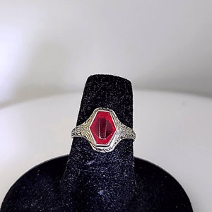 May include: A silver ring with a red octagon-shaped gemstone set in a filigree design.