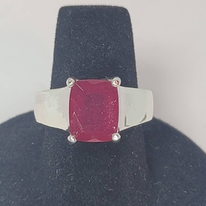 May include: A silver ring with a large, red, rectangular gemstone.