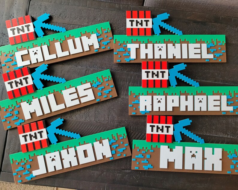 May include: Six Minecraft-themed nameplates with different names, each featuring a TNT block, a pickaxe, and a green grass background. The names are Callum, Miles, Jaxon, Thaniel, Raphael, and Max.