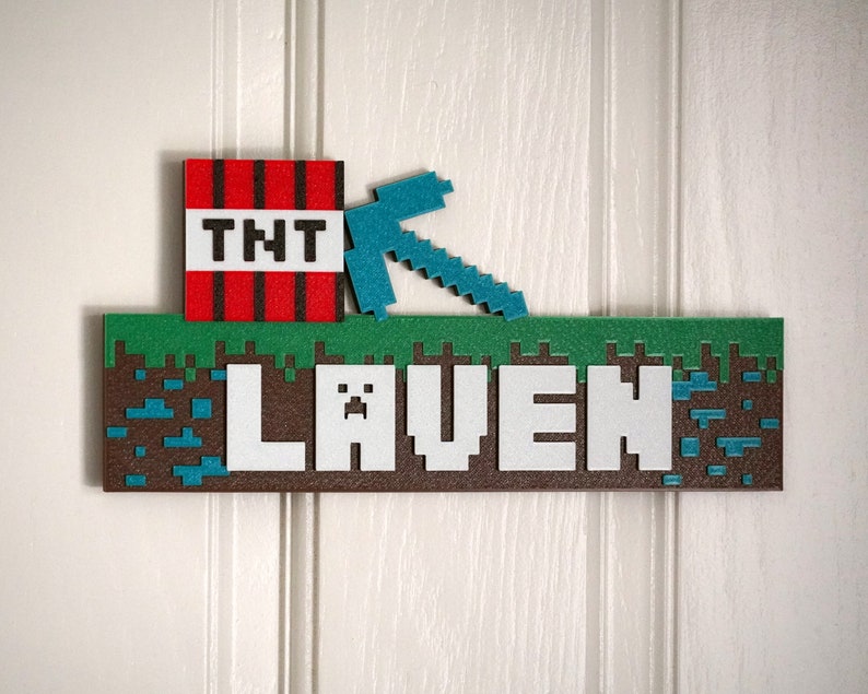 May include: A Minecraft-themed name sign with the name "Laven" in white letters on a brown background. The sign features a green grass block, a blue pickaxe, and a red TNT block.