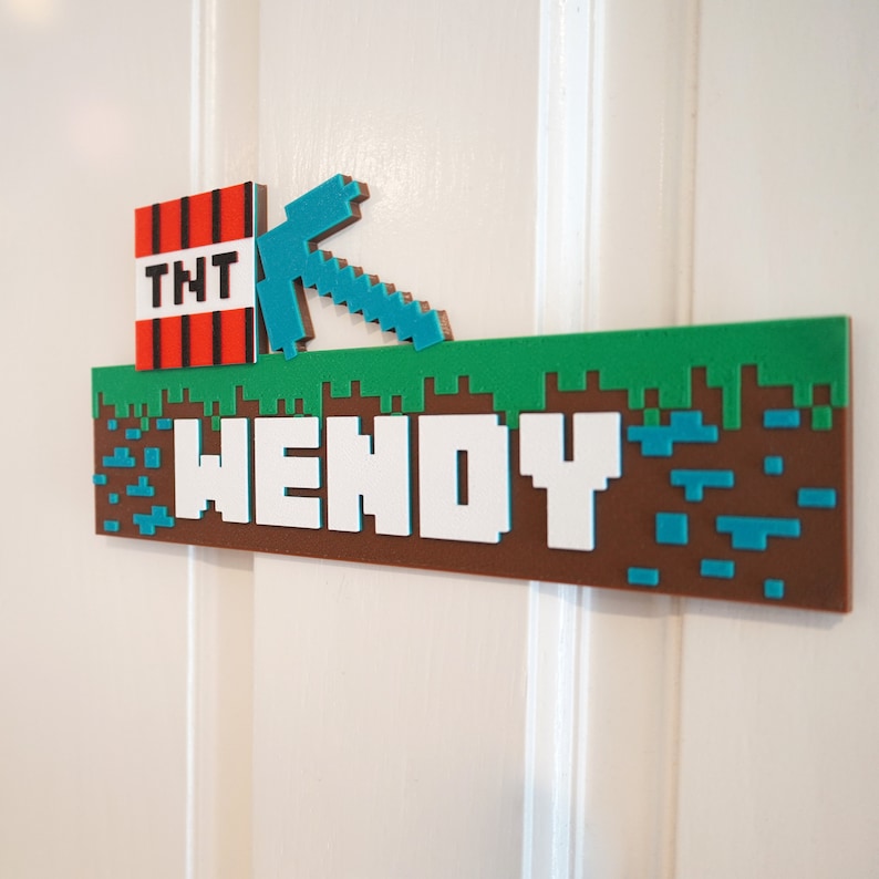 May include: A Minecraft-themed nameplate with the name "WENDY" in white pixelated letters on a brown background. The nameplate has a green grass top with a blue pickaxe and a red TNT block.