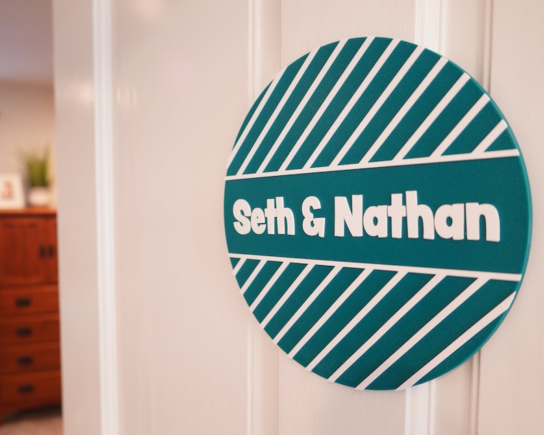 May include: Teal and white striped round sign with the text "Seth & Nathan" in white.