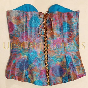 May include: A turquoise and pink floral patterned corset with a brown lace-up back.