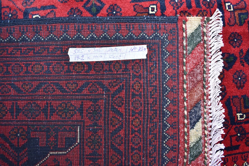 May include: Close-up of a red and blue rug with a fringe border. A handwritten label reads "5.85 x 10.75 meters / 19.2 x 35.2 feet".