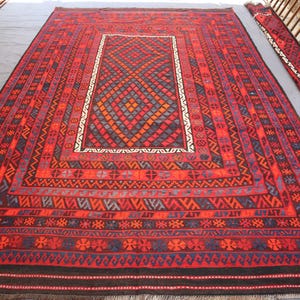 Pu&ograve; includere: Un grande tappeto rettangolare rosso con intricati motivi geometrici nelle tonalit&agrave; del rosso, blu e nero. Il tappeto presenta un disegno centrale a diamante e un bordo bianco. Sono visibili anche due corridori pi&ugrave; piccoli abbinati.