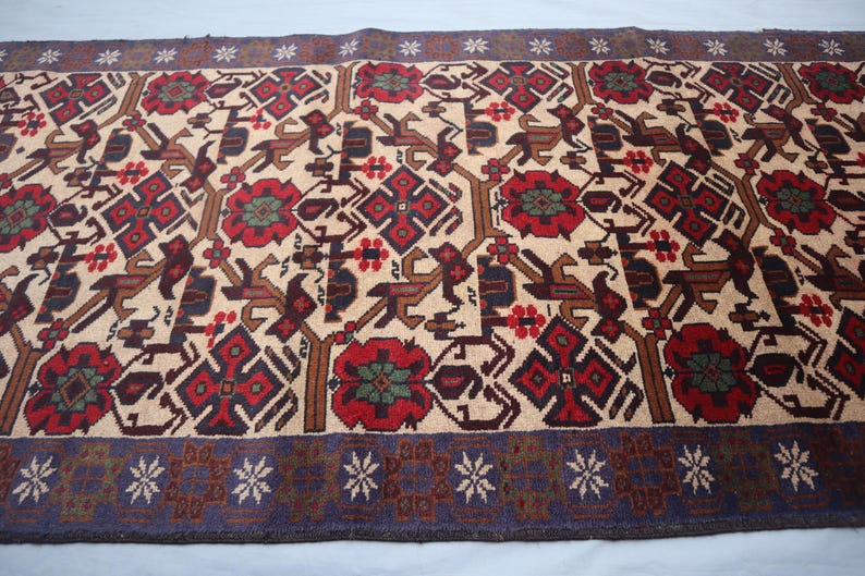May include: A rectangular rug featuring a beige backdrop with a repeating pattern of red, brown, and dark blue geometric shapes and floral motifs. The rug has a dark blue border with white star-like designs.