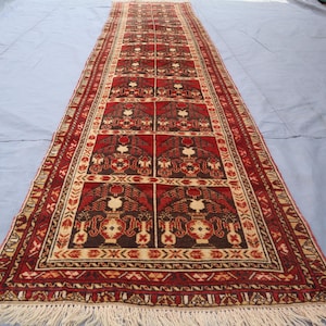 May include: A long, narrow red and cream colored rug with a traditional Persian design. The rug has a fringe on both ends.