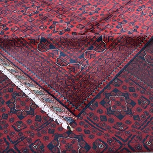 May include: A red and blue patterned rug with a fringe border. The rug is folded in half, showing the intricate design.