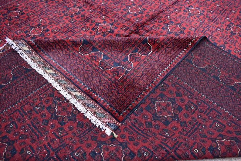 May include: A red and blue patterned rug with a fringe border. The rug is folded in half, showing the intricate design.
