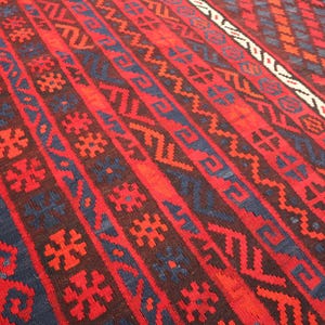 Pu&ograve; includere: Un vivace tappeto tessuto a mano con un ricco arazzo di colori. Il design presenta audaci motivi geometrici rossi, blu scuro e marroni. I dettagli intricati e i toni caldi del tappeto creano un tessuto visivamente accattivante.