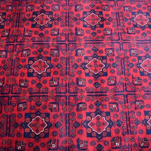May include: A red rug with a repeating pattern of blue and white geometric shapes. The rug has a traditional Persian design.