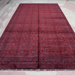 May include: A large, red and blue patterned rug with a detailed border. The rug has a traditional design and is made of wool.