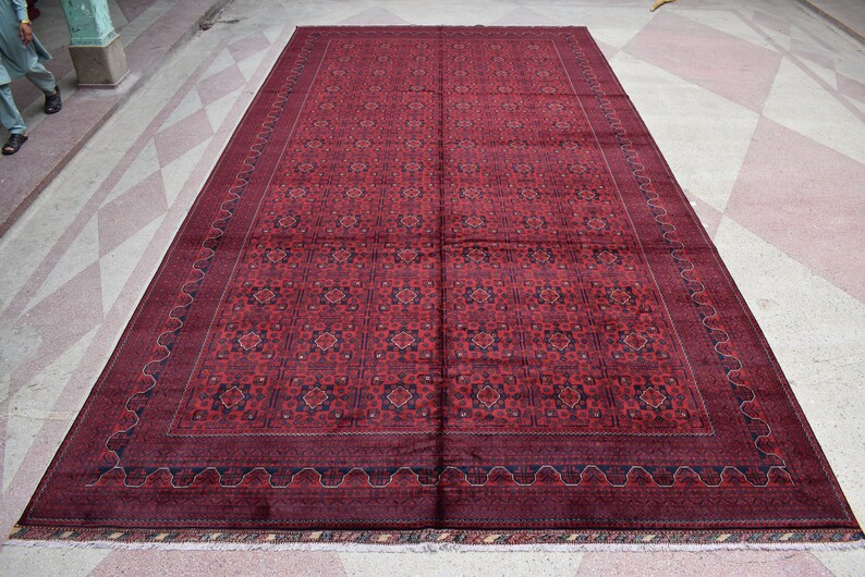 May include: A large, red and blue patterned rug with a detailed border. The rug has a traditional design and is made of wool.