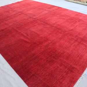 May include: A solid red rug with a subtle texture and a fringed edge.