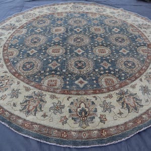 May include: A round rug with a blue and cream colored pattern. The rug has a floral design with a central medallion.