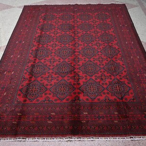 Puede incluir: Una alfombra roja con un dise&ntilde;o estampado en azul oscuro y rojo. La alfombra tiene un borde con flecos.