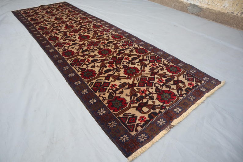 May include: A long, rectangular runner rug featuring a beige field with a repeating pattern of red and brown floral and geometric designs. The border is dark brown with small white star-like shapes. The rug has a fringed edge.