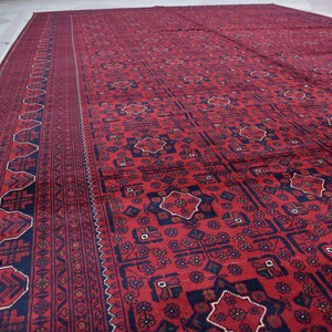 May include: A red and black patterned rug with a geometric design. The rug has a border with a repeating pattern.