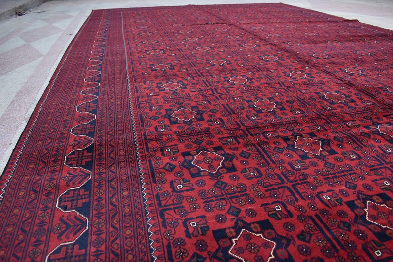 May include: A red and black patterned rug with a geometric design. The rug has a border with a repeating pattern.