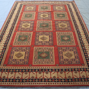 May include: A red, beige and black patterned rug with a geometric design. The rug has a border with a repeating pattern of stylised leaves.
