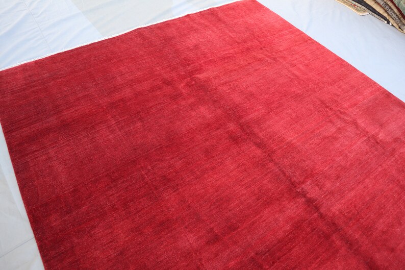 May include: A solid red rug with a smooth, slightly textured surface. The rug is made of a soft, plush material.