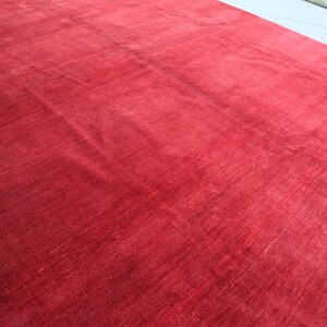 May include: A solid red rug with a smooth, slightly textured surface. The rug is made of a soft, plush material.