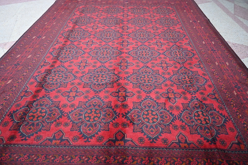 Puede incluir: Una alfombra roja con un patr&oacute;n geom&eacute;trico en blanco y negro. La alfombra tiene un borde con un dise&ntilde;o floral.