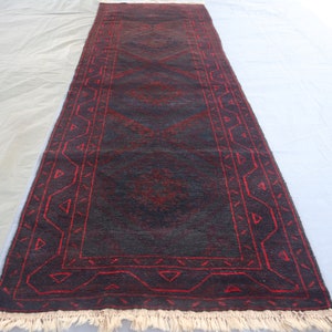 May include: A dark blue and red runner rug with a geometric pattern. The rug has a fringe border.