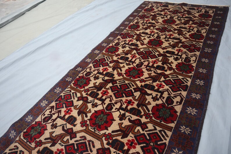 May include: A rectangular rug featuring a beige field with a repeating pattern of red flowers, brown geometric shapes, and dark brown borders. The rug has a dark blue border with white star-like designs.