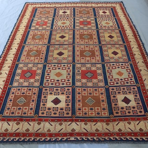 May include: A traditional rug with a geometric pattern in shades of red, blue, and beige. The rug features a repeating design of squares and diamonds.