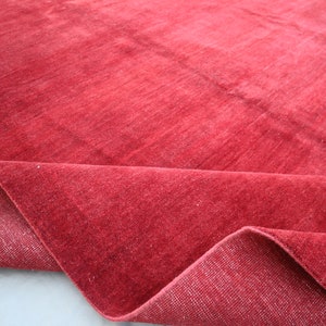 May include: A close-up of a red rug with a soft, plush texture. The rug is folded in half, revealing the underside.