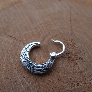 May include: Silver hoop earrings with a Celtic knot design.