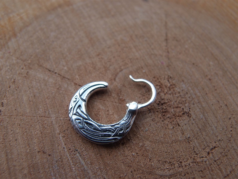 May include: Silver hoop earrings with a Celtic knot design.