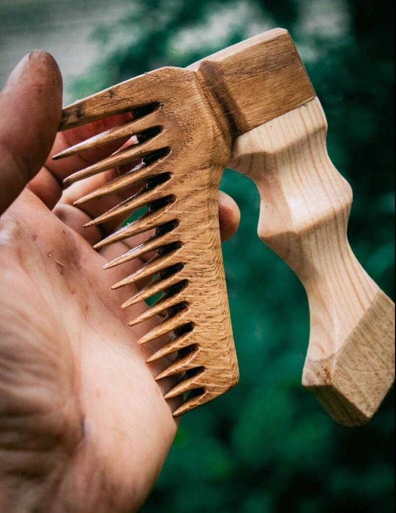 May include: A wooden comb with a long, curved handle. The comb is made of light brown wood and has a natural finish. The handle is made of a darker wood and has a smooth, polished finish.