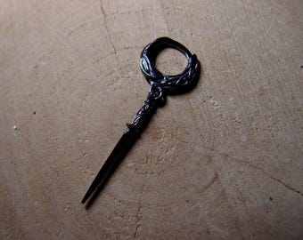 Könnte beinhalten: Ein schwarzer Metalls Schlüssel mit einem dekorativen, verzierten Design. Der Schlüssel hat eine kreisförmige Schlaufe oben und eine lange, spitze Spitze.