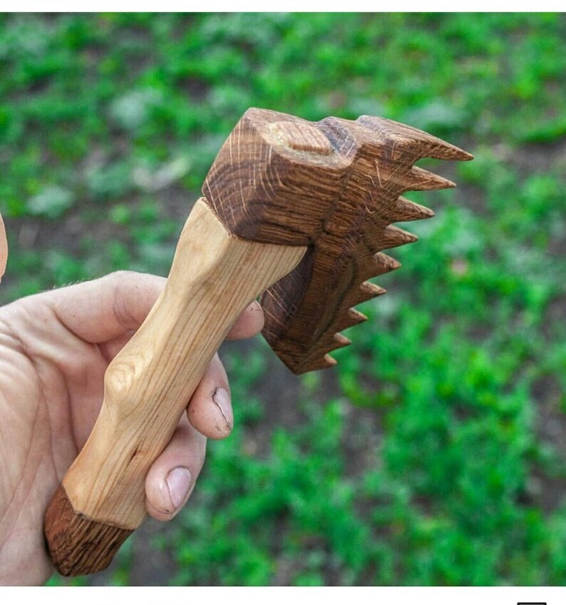 May include: A wooden hand-carved tool with a handle and a comb-like head. The tool is made of light and dark wood.
