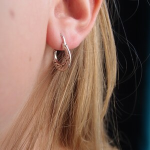 May include: A pair of silver hoop earrings with a Celtic knot design.