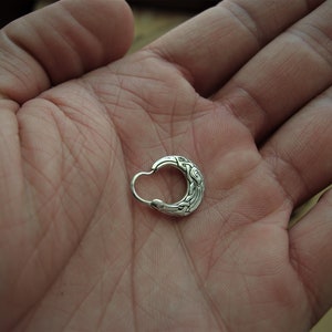 May include: A silver hoop earring with an intricate Celtic knot design.