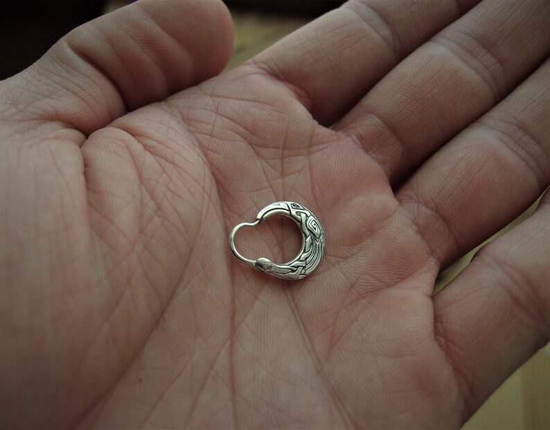 May include: A silver hoop earring with an intricate Celtic knot design.