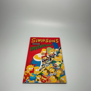 May include: A comic book titled "Simpsons Comics Spectacular" featuring the Simpson family and other characters. The cover is red with the title in yellow and green. The comic book is rectangular and has a glossy finish.
